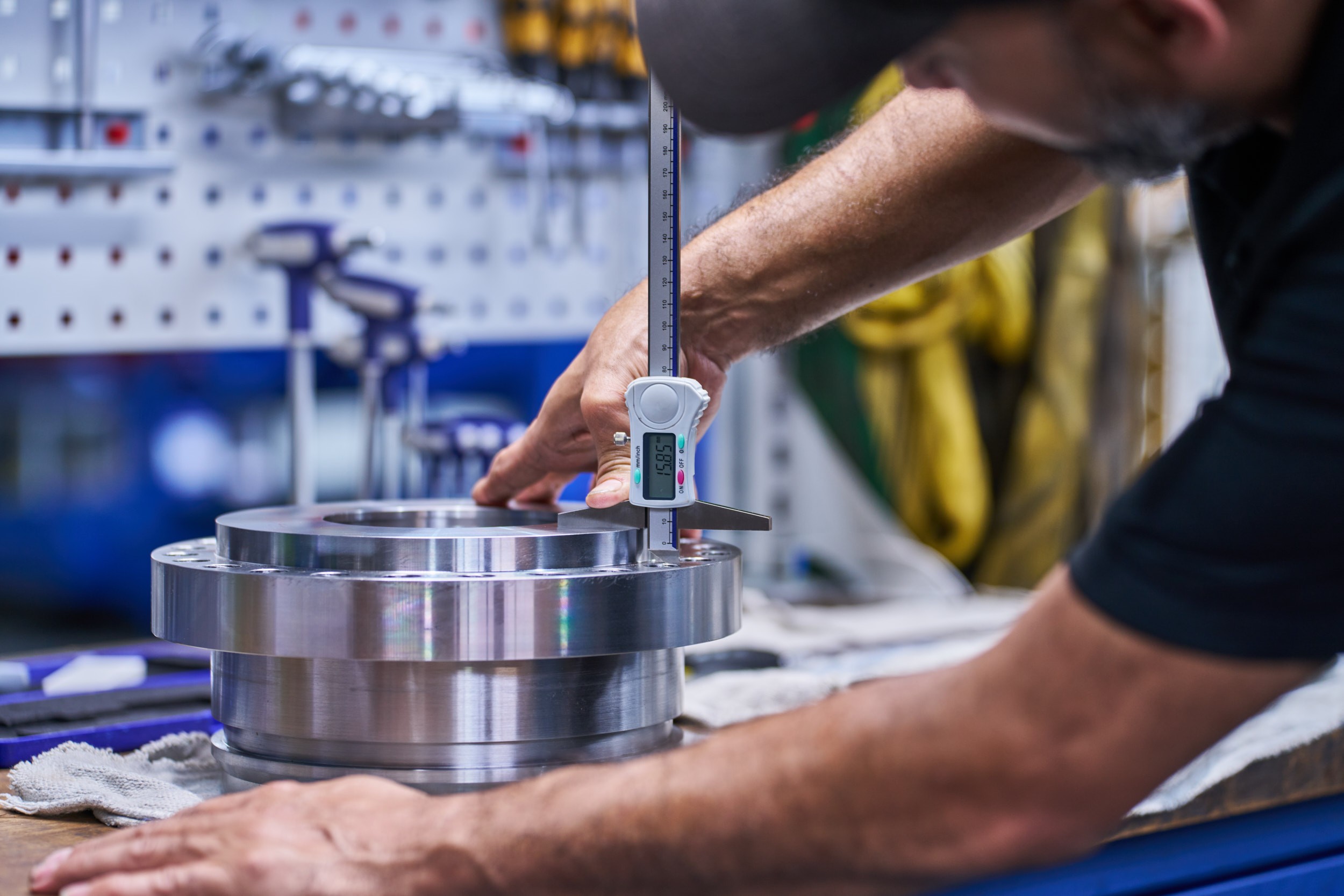 Ein Mitarbeiter von ACONA pr&uuml;ft an einem Hydraulikzylinder-Bauteil bestimmte Ma&szlig;e