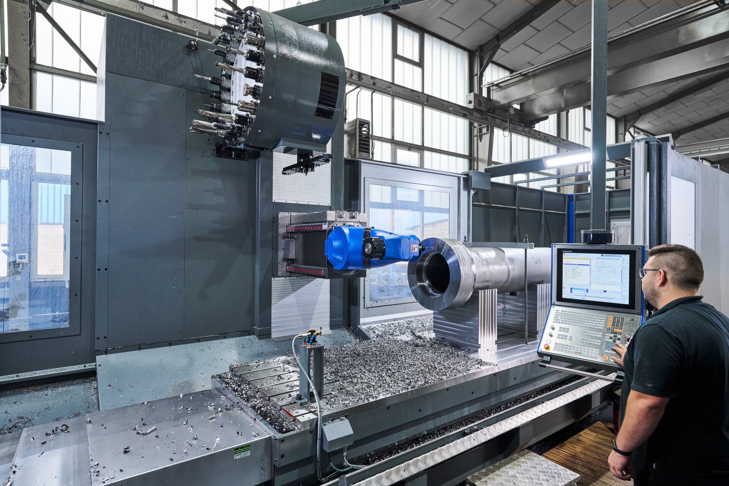 Ein ACONA Mitarbeiter bedient eine Maschine, die ein Bauteil eines Hydraulikzylinders fr&auml;st